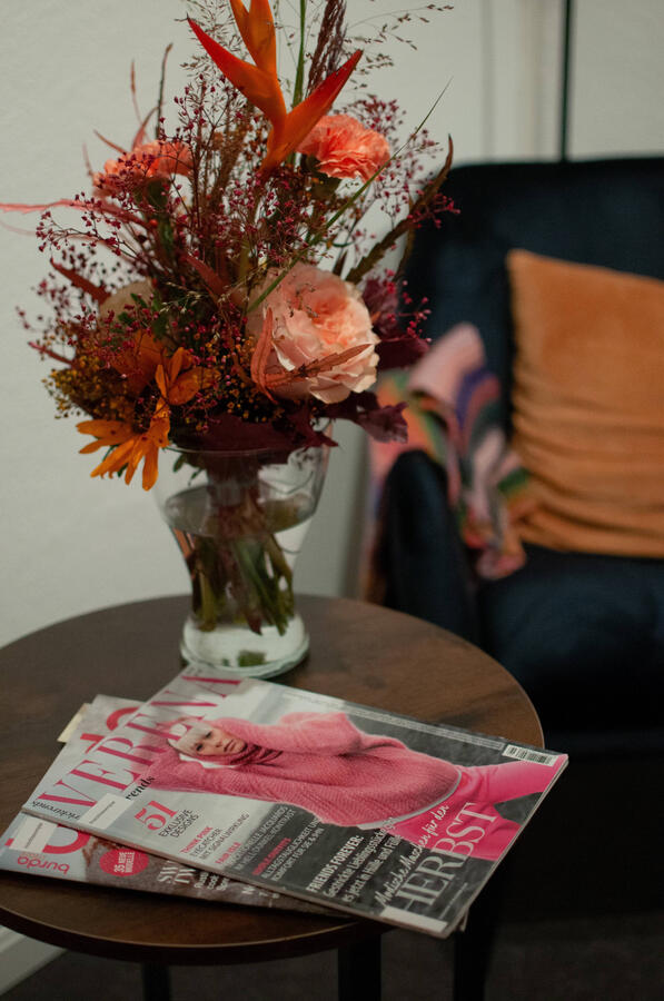 Ein Blumenstrauß steht auf einem Beistelltisch neben einer Fachzeitschrift.